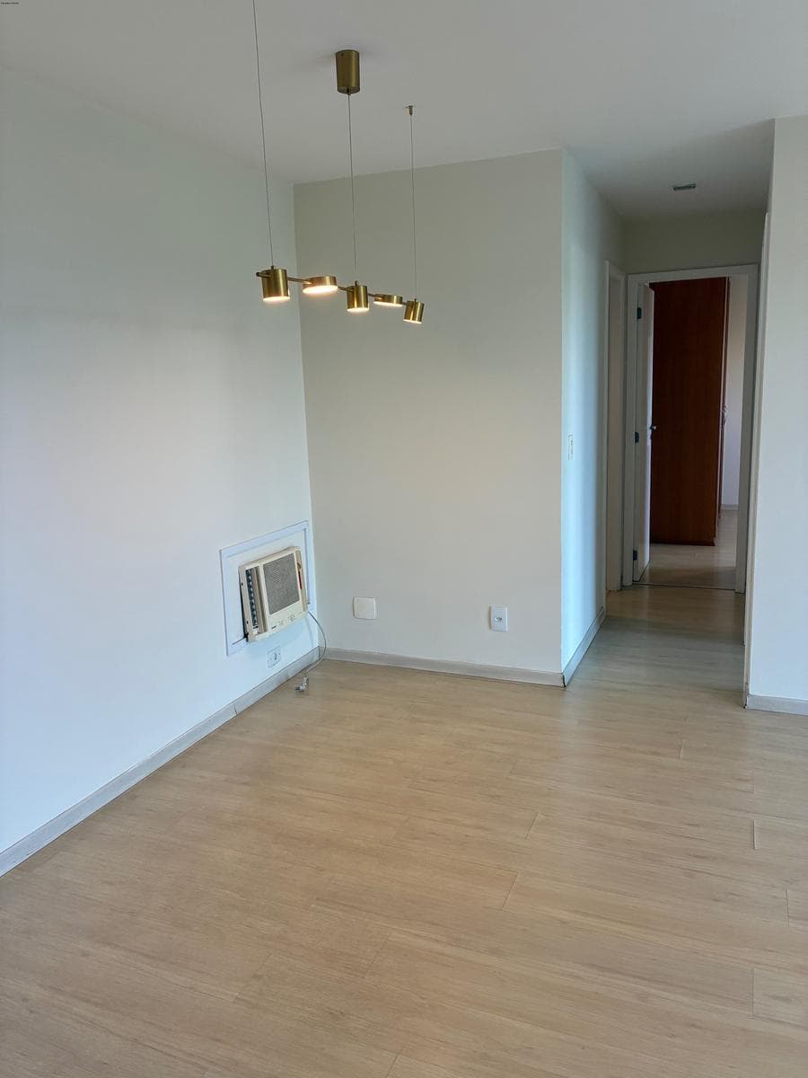 Sala de estar com piso amadeirado, ar-condicionado e luminária pendente.