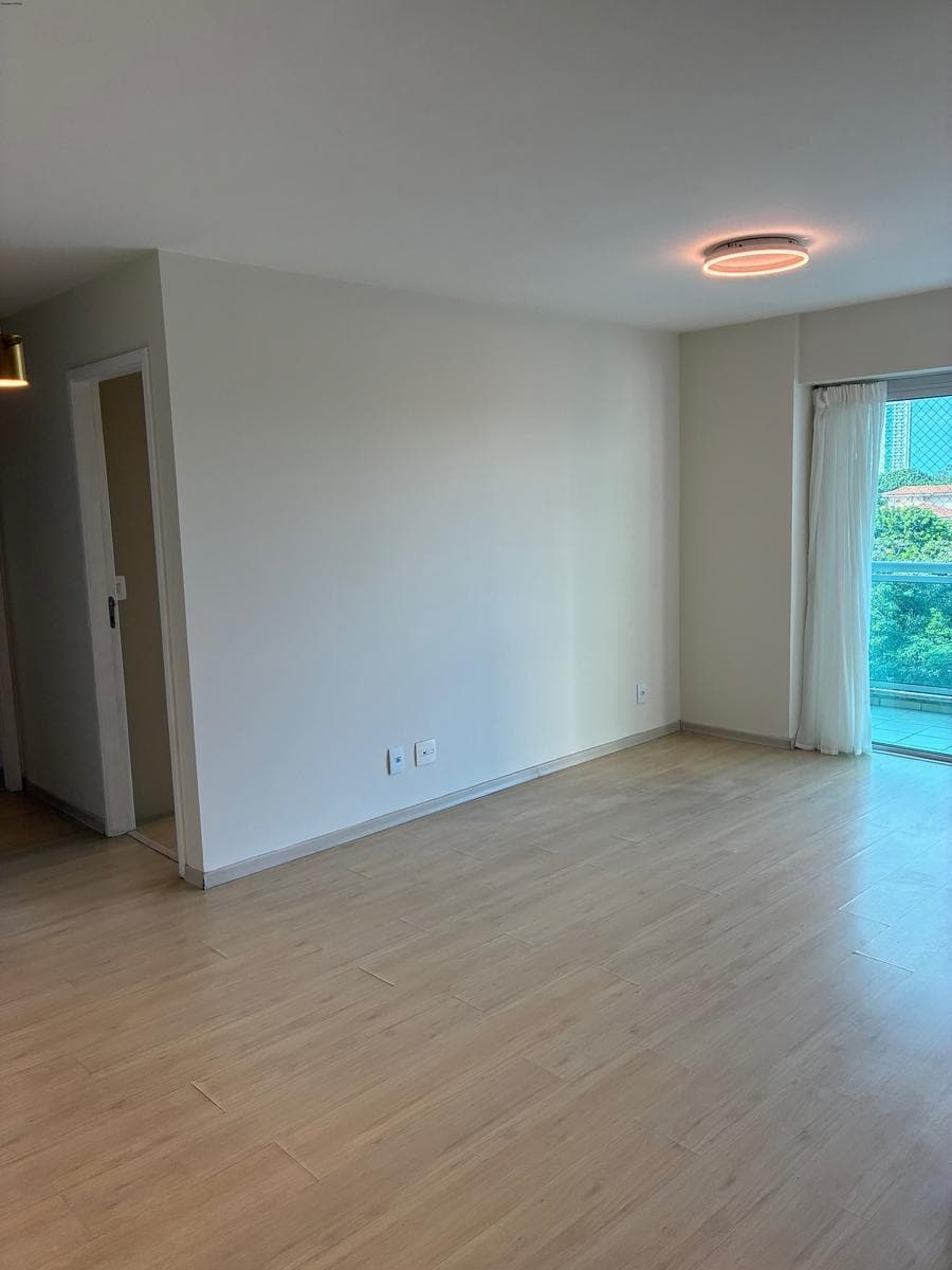 Ambiente de sala integrado com piso laminado e acesso à varanda.